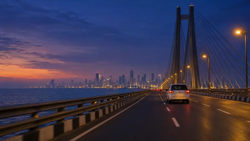 A white MPV driving along the Bandra–Worli Sea Link at dusk