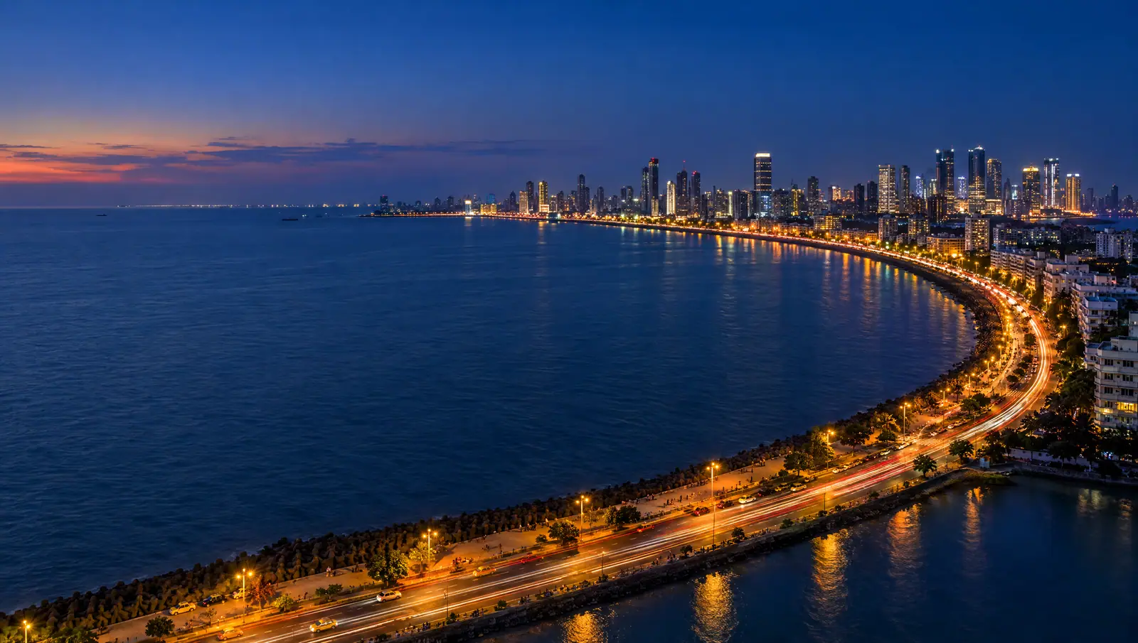 Marine Drive in Mumbai at dusk, the Queen’s Necklace curve of streetlights and traffic trails leading to the Nariman Point skyline